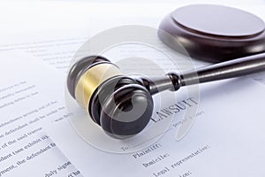 Closeup shot of a gavel and lawsuit papers on a white surface