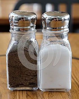Closeup shot of glass salt and pepper shakers on a wooden background