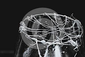 Closeup shot of glue stick strings on a glass with water droplets on a dark background