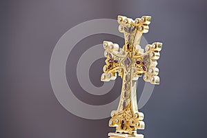 Closeup shot of a gold Armenian cross on a gray background