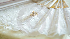 Closeup shot of gold earrings on a white fan