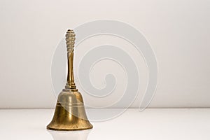 Closeup shot of a golden handbell on a white wall background