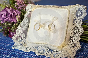 Closeup shot of golden wedding rings on a small cushion