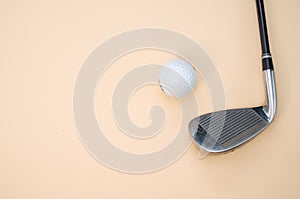 Closeup shot of a golf ball and a club isolated on a pink background