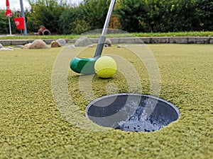 Closeup shot of a golf club pushing a ball into a hole