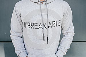 Closeup shot of a gray hoody with printing UNBREAKABLE.