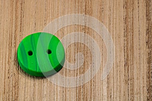 Closeup shot of a green button put on a wooden surface