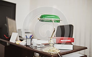 Closeup shot of a green desktop lamp at an office with books and files