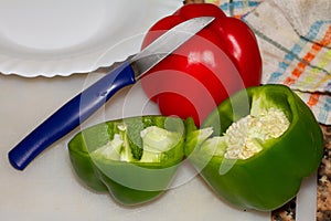 Closeup shot of green and red bell peppers cut in half using a small knife