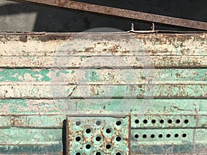Closeup shot of a green rusty metal gate with holes outdoors