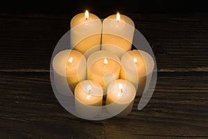 Closeup shot of a group of seven burning candles with black background