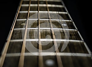 A closeup shot of a guitar fretboard using shallow depth of filed and black background