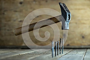 Closeup shot of a hammer floating above the nails on the wooden ground