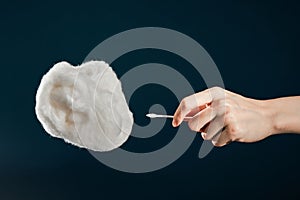 Closeup shot of a hand holding cotton bud from cotton isolated on dark background