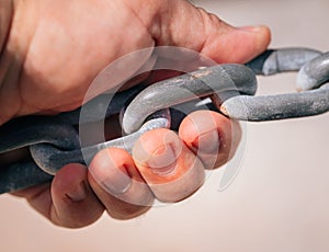 Closeup shot of a hand holding grey metal chain