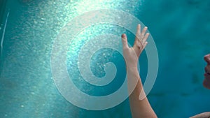 Closeup shot of a hand of a woman walking insiade of an oceanarium pipe touching the glass