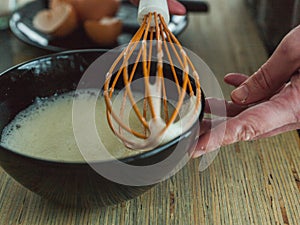 Closeup shot of the hands of the cook beating eggs with a whisk - perfect for a recipe article
