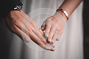 Closeup shot of the hands of newly married groom and the bride holding hands and wearing rings