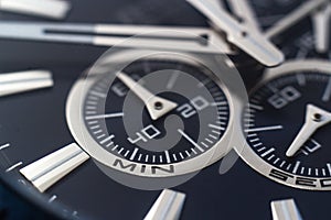 Closeup shot of the hands, numbers and hour marks of a black watch