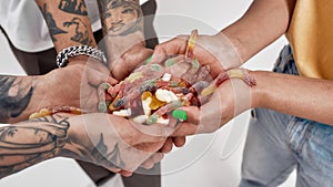 Closeup shot of hands of young people holding colorful sour sugar gummy worm candies
