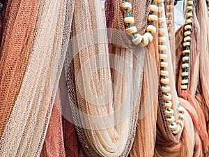 Closeup shot of hanging multicolored fishing nets and white beads on a green rope