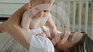 Closeup shot of happy young mother having fun with her baby son on bed at bedroom