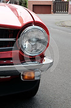 Closeup shot of headlights of a red vintage car in a street
