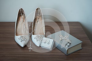 Closeup shot of  heels with a necklace earrings in a box and the holy bible with  rings on it
