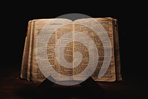 Closeup shot of a historic old Bible open on the Zephaniah pages on display in a dark room photo