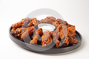 Closeup shot of hot and spicy buffalo chicken wings on a white background with blue cheese dip