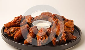 Closeup shot of hot and spicy buffalo chicken wings on a white background with blue cheese dip