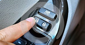 Closeup shot of human finger pressing the unlock button in a car door instrument panel