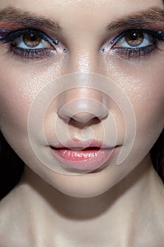 Closeup shot of human woman face. Female with face and eyes beauty makeup with blue eye shadow make up and rhinestones