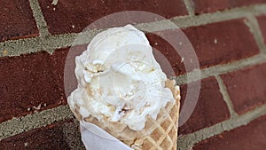 Closeup shot of ice cream in a waffle with brown brick wall in the background