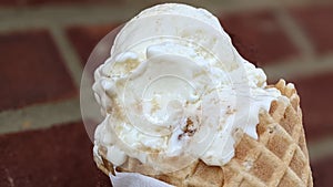 Closeup shot of ice cream in a waffle with brown brick wall in the background