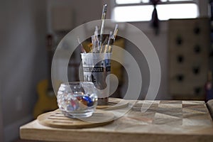 Closeup shot of a jar of marbles and cup of paint brushes indoors