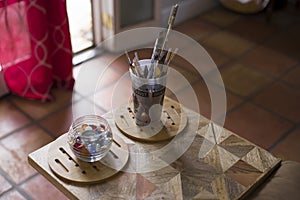Closeup shot of a jar of marbles and cup of paint brushes indoors