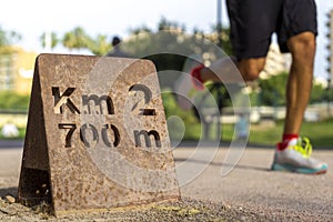 Closeup shot of a Km 2, 700 m sign on a blurred background of an unrecognizable running man