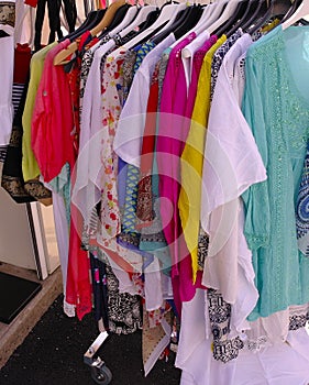 Closeup shot of ladies' colorful blouses on hangers from a street shop