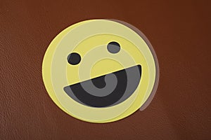 Closeup shot of a laughing smiley face sign on a brown background