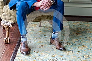 Closeup shot of the legs of the groom sitting on the chair and waiting for the ceremony