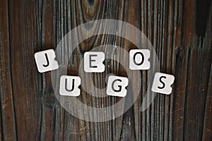 Closeup shot of letters cubes forming the word Juegos on a wooden surface photo