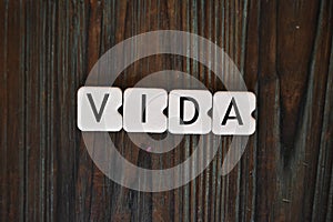 Closeup shot of letters cubes forming the word VIDA, meaning lifetime on a wooden surface