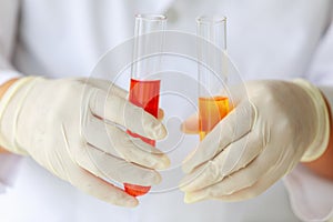 Closeup shot of liquid in glass in test tube holded by scientist in white lab coat and rubber gloves hands