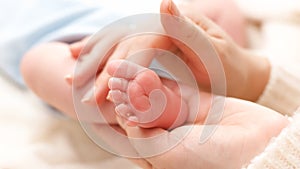 Closeup shot of little newborn baby feet in gentle mothers hands. Concept of family happiness and loving parents with