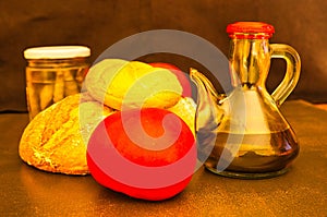 Closeup shot of loaves of bread, tomatoes, and a bottle of vinegar on a brown surface