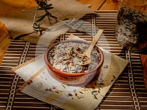Closeup shot of long grain wild rice in a plate with a wooden spoon on a piece table cover