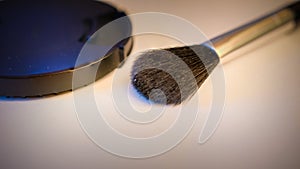 Closeup shot of makeup brush and compact cream powder isolated on dark peach background