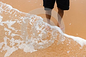 Closeup shot of male feet on smooth sand at the beach