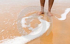 Closeup shot of male feet on smooth sand at the beach